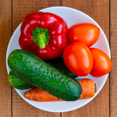 Cucumbers and tomatoes on a white plate. A plate with vegetables on the table. Diet food. Vegetarian food.
