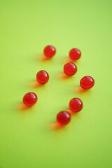 Obraz premium Round red vitamins on a green table
