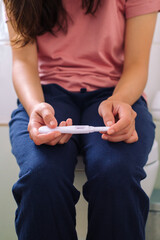 Cropped image of woman holding a pregnancy test on her knees