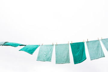 Blue and green towels hanging and drying after washing, with a clean and clear sky
