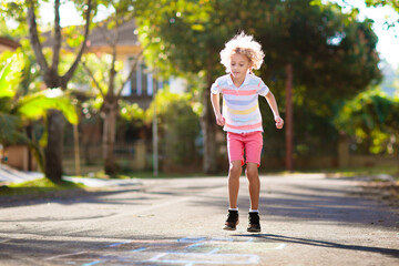 Kids play hopscotch in summer park. Outdoor game.