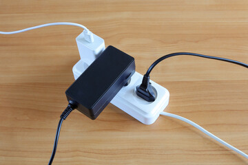 Different devices plugs are connected to multiple outlets of energy on wooden surface