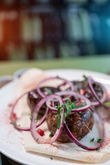 georgian fried pork sausages kupaty with onion, cilantro on pita on white plate