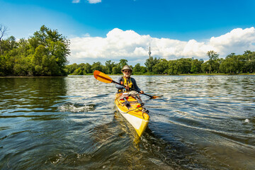A bearded male paddler practices his bracing technique in a sea kayak  on a pond in the Toronto Islands on a warm sunny summer afternoon.  Room for text.