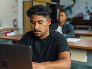 Obraz premium Native boy students sit in class with a laptop and a pencil and paper