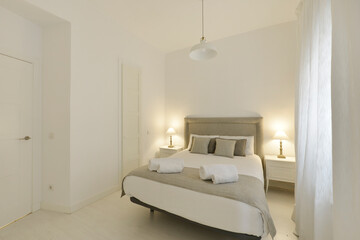 Bedroom with double bed, off-white painted walls, headboard upholstered in gray fabric, matching...