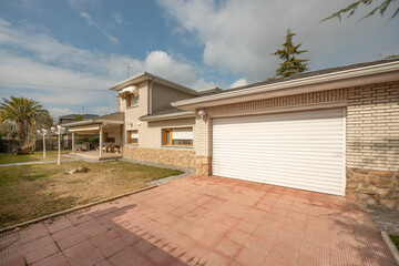 White aluminum door of a garage in stone and white brick single family house