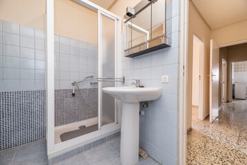 Tiled bathroom with blue tiles and mosaic, white porcelain sink with matching pedestal, chrome...