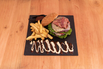 Delicious double beef burger with melted cheese, fried bacon, lettuce and tomato, sauces and homemade fries