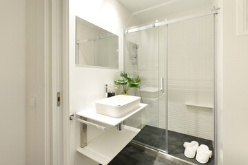 Bathroom with marble tiles, wooden cabinet with drawers, shower cabin with glass partitions, chrome 