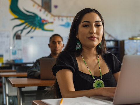 Native girl looking into the camera while typing on her computer