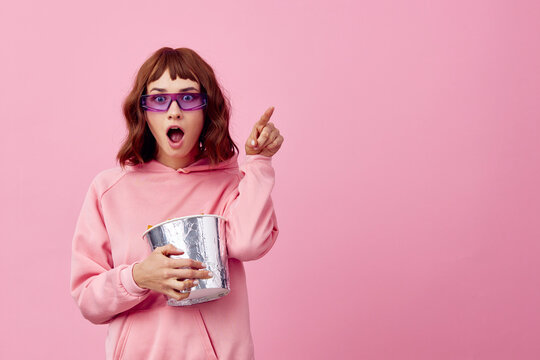 Excited overjoyed happy cute redhead lady in pink hoodie sunglasses with popcorn posing isolated on over pink studio background show copy space Banner. Fashion Cinema concept. Entertainment offer