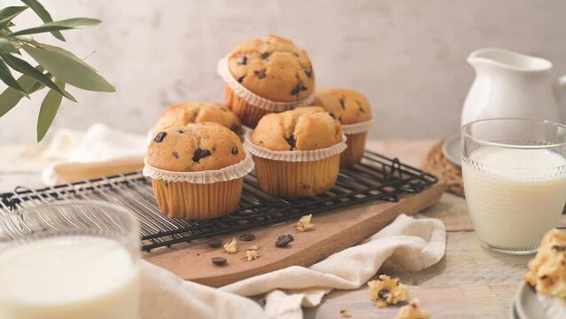 Chocolate chip muffins with milk served on glass cups on white kitchen countertop.