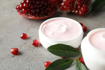 Natural facial mask, pomegranate seeds and green leaves on light grey table, closeup