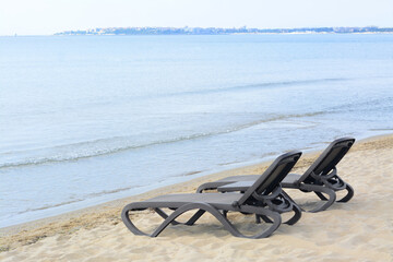 Obraz premium Empty black sunbeds near water on sea beach