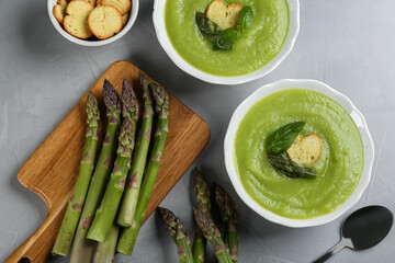 Delicious asparagus soup served on grey table, flat lay