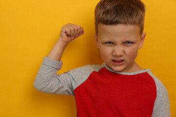 Angry little boy on yellow background. Aggressive behavior - obrazy, fototapety, plakaty