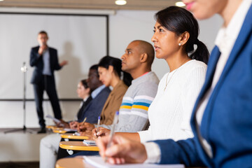 Portrait of interested hispanic female entrepreneur sitting in conference hall at business event....