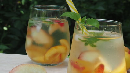 Summer drinks, with mint and peach cocktails with ice in glasses. Refreshing summer homemade Alcoholic or non-alcoholic cocktailsor Detox infused flavored water