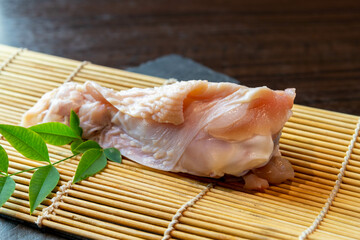 和食レストランや居酒屋の厨房で調理される、竹すだれの上に乗せられた新鮮な地鶏の手羽元。テキストを入れるスペースあり