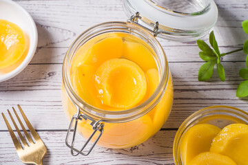 sweet canned yellow peach in glass jar on table