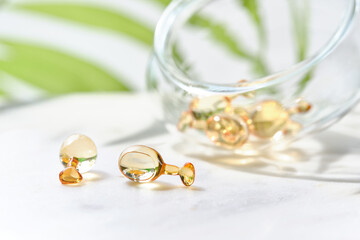 Serum capsules for healthy skin. Anti-wrinkle rejuvenation skin treatment. Beauty product presentation. Off white background with green palm leaf.