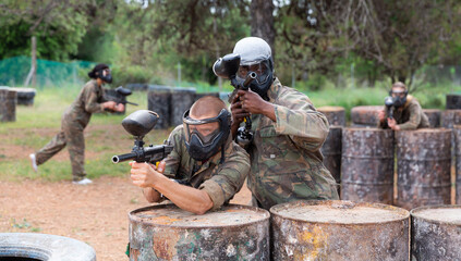 Fototapeta premium Two men in camouflage and masks holding guns ready for playing paintball with friends