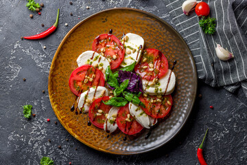 Caprese salad with mozzarella and tomato with basil and cream balsamic on brown plate top view