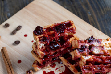 soft waffles with red cherry jam on a serving board