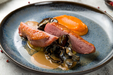 Duck breast with black mushrooms and mashed pumpkin on plate macro close up