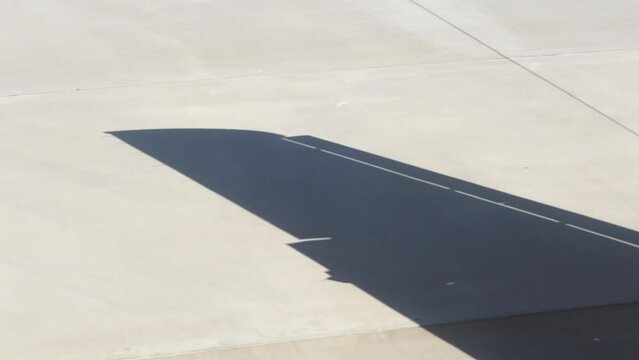 Airplane lands on airfield. Shadow of airplane wing casts on asphalt on sunny day closeup. Plane drives to airport terminal after landing