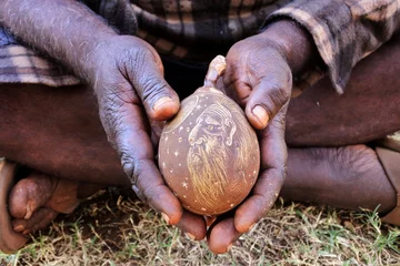 Gordijnen Indigenous Australian aboriginal man hands holding an engraved boab tree nut shell © Rafael Ben-Ari
