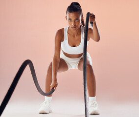 Fit woman doing cardio workout with ropes, exercising for fitness training and looking sporty while...