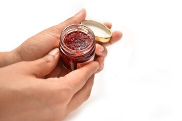 A girl Holding a bottle of cosmetic. The scrub is made out of fresh strawberries. 