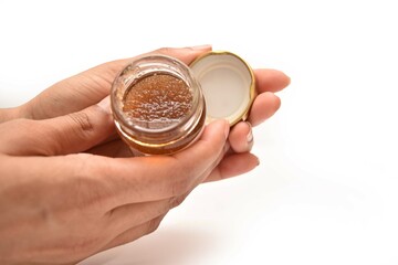 A girl Holding a bottle of cosmetic. he scrub is made out of  pure honey.