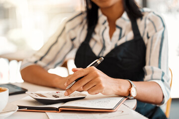 Hands of business owner taking orders, calculating profit and working on budget for startup while...