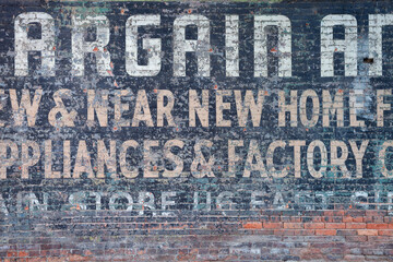 Old grungy brick wall with peeling paint and lettering