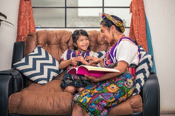 Latina mother and daughter enjoy spending time together reading a book.