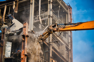 Hydraulic cutter of crane demolishes old industrial building