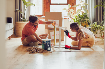 Couple painting wooden table by recycle, donate and thrift furniture for a new home improvement project in new apartment. Creative and DIY man and woman with reusable objects, decorating their house
