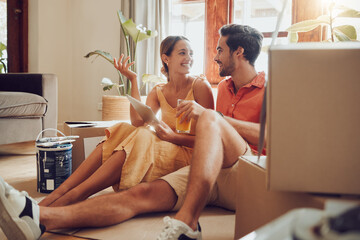 Home owner couple taking a break from painting, moving into new house or remodeling living room interior design. Husband, wife searching home improvement ideas online with tablet on a relaxing day