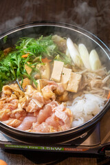 煮込まれ沸騰し湯気の立つ鶏肉のすき焼き鍋