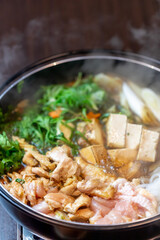 煮込まれ沸騰し湯気の立つ鶏肉のすき焼き鍋