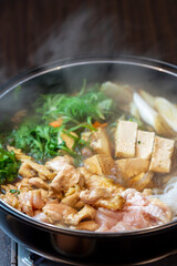 煮込まれ沸騰し湯気の立つ鶏肉のすき焼き鍋