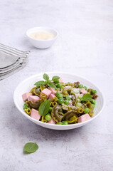 Green pasta with peas, sausages and cheese