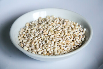 Fototapeta premium Bowl of organic pearl barley on white plate