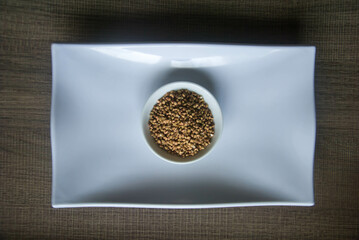 Raw Buckwheat in white ceramic bowl on wooden wood