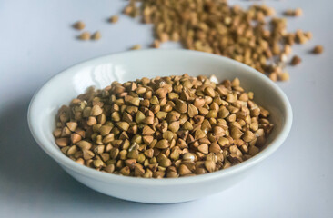 Raw Buckwheat in white ceramic bowl on wooden wood