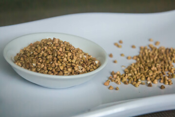 Raw Buckwheat in white ceramic bowl on wooden wood