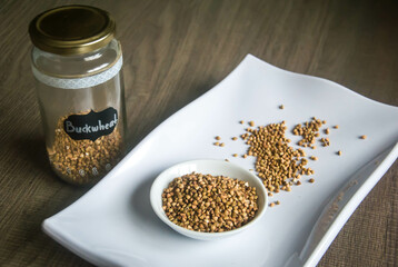 Raw Buckwheat in white ceramic bowl on wooden wood